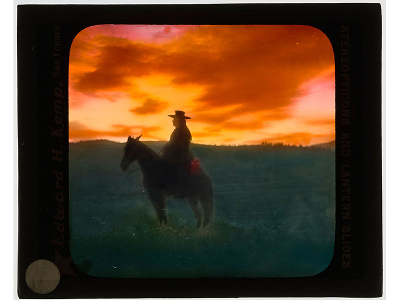 Silhouette of man on horseback with sunset in background.